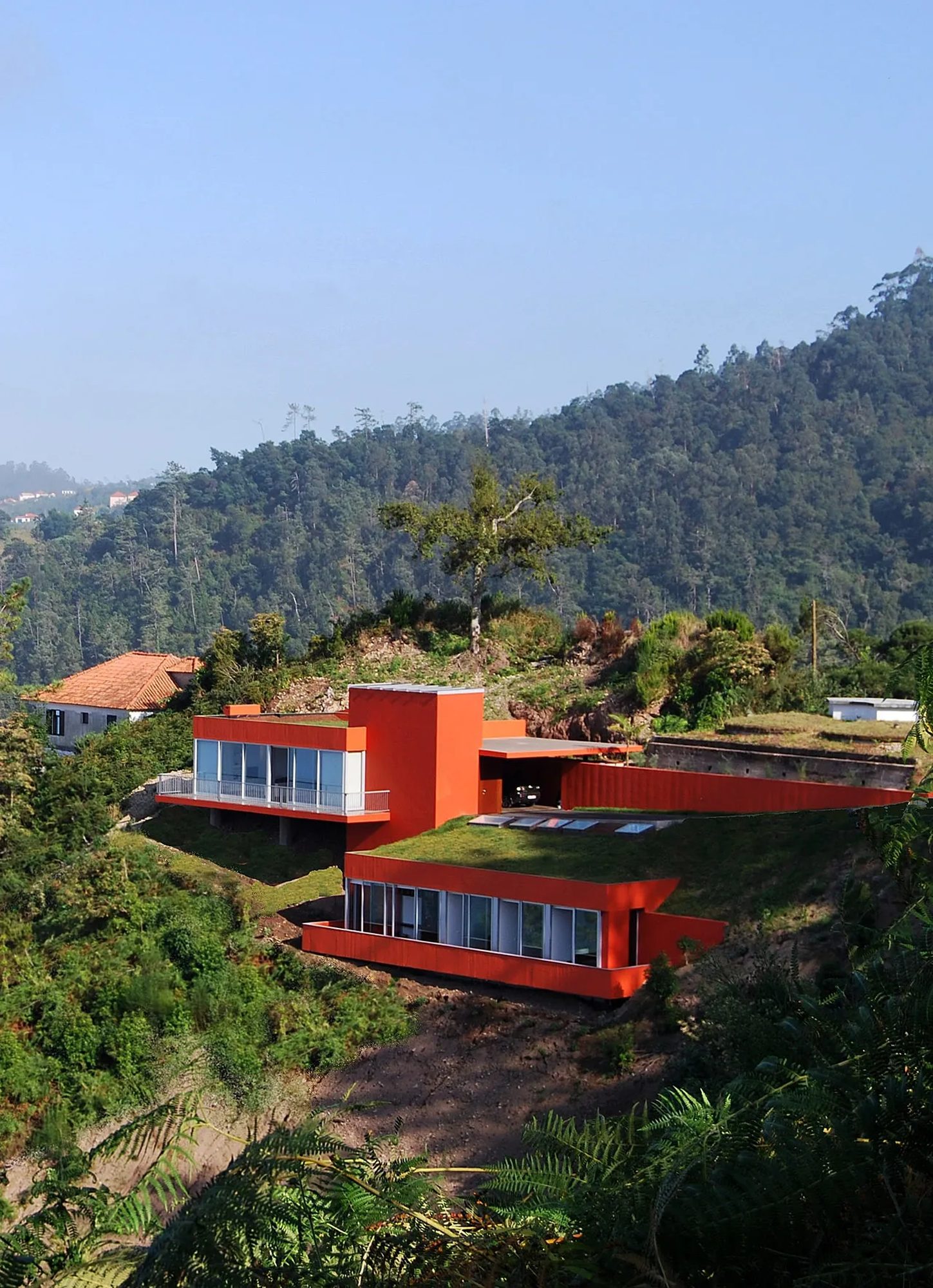 Die orangefarbene Villa terrassiert in einen grünen Hang von Santana, Wald dahinter
