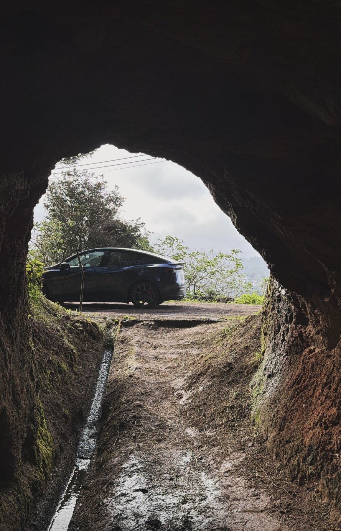 The Tesla seen through a levada tunnel cut into the rock, a water channel running along the path