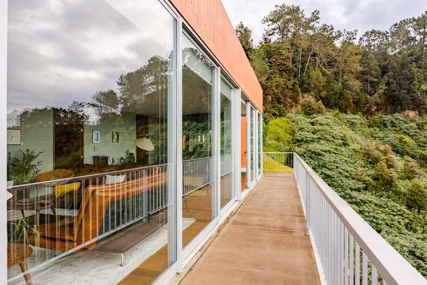 Upstairs balcony with a white railing and glass doors looking into the living room