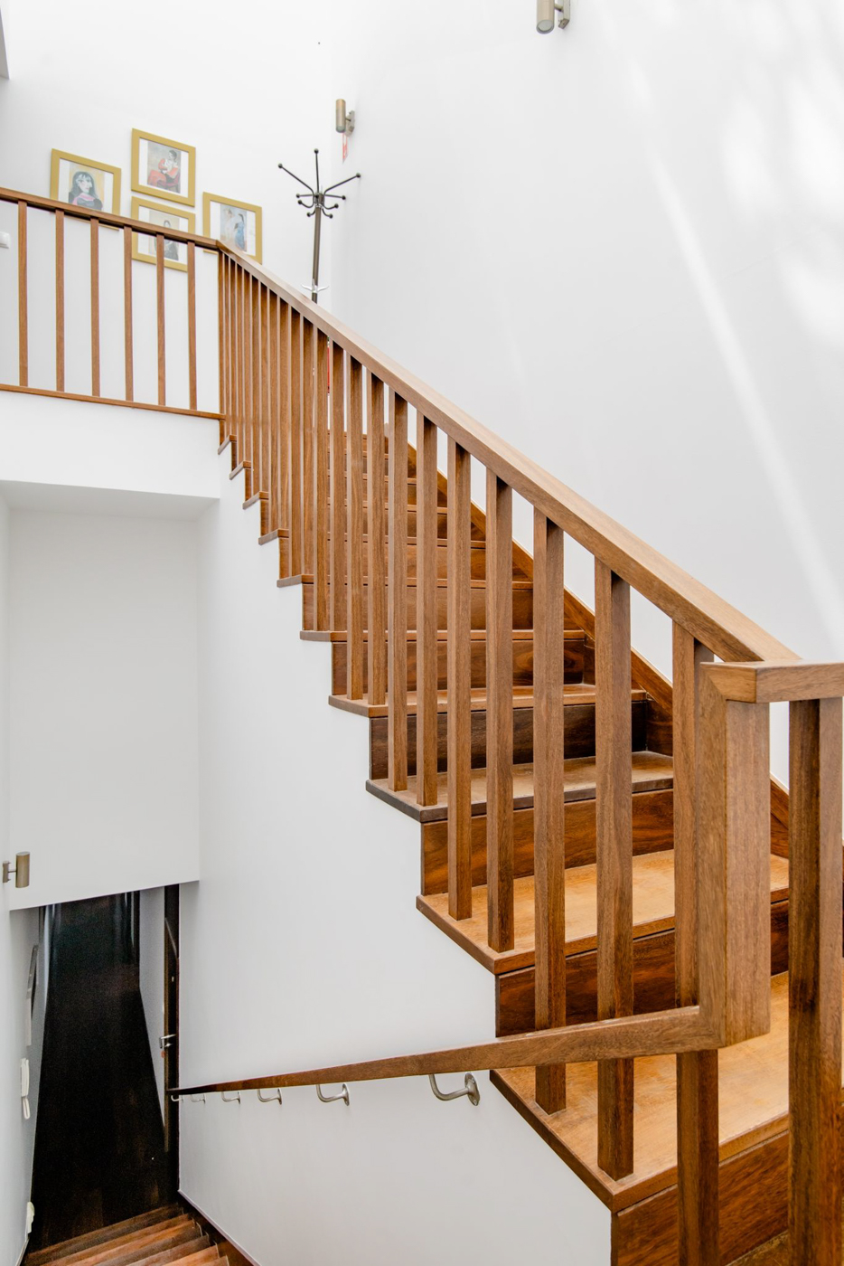 Looking up the dark wood staircase with a slatted rail and white walls