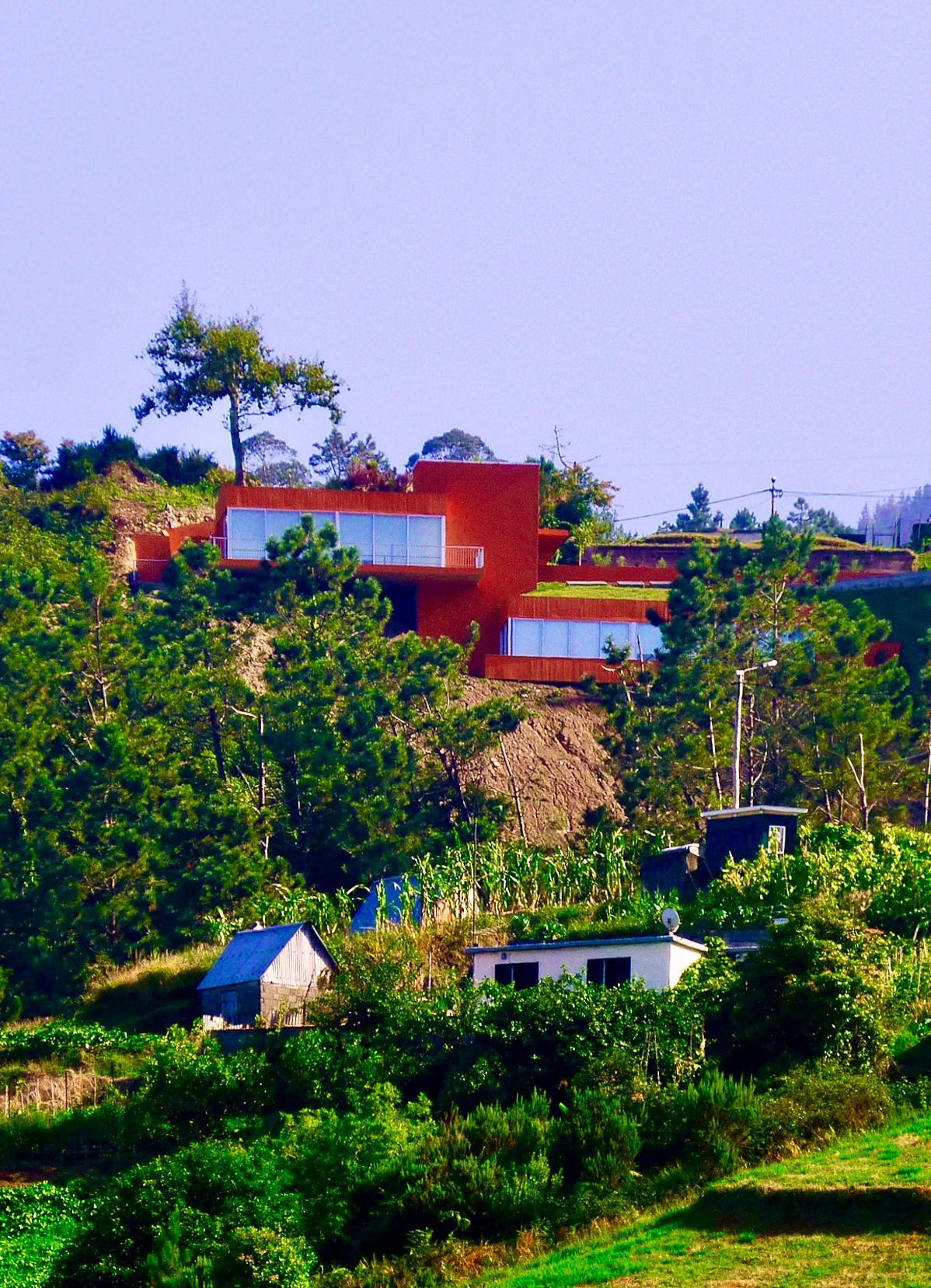 Orange villa on the hillside, with a small white building below
