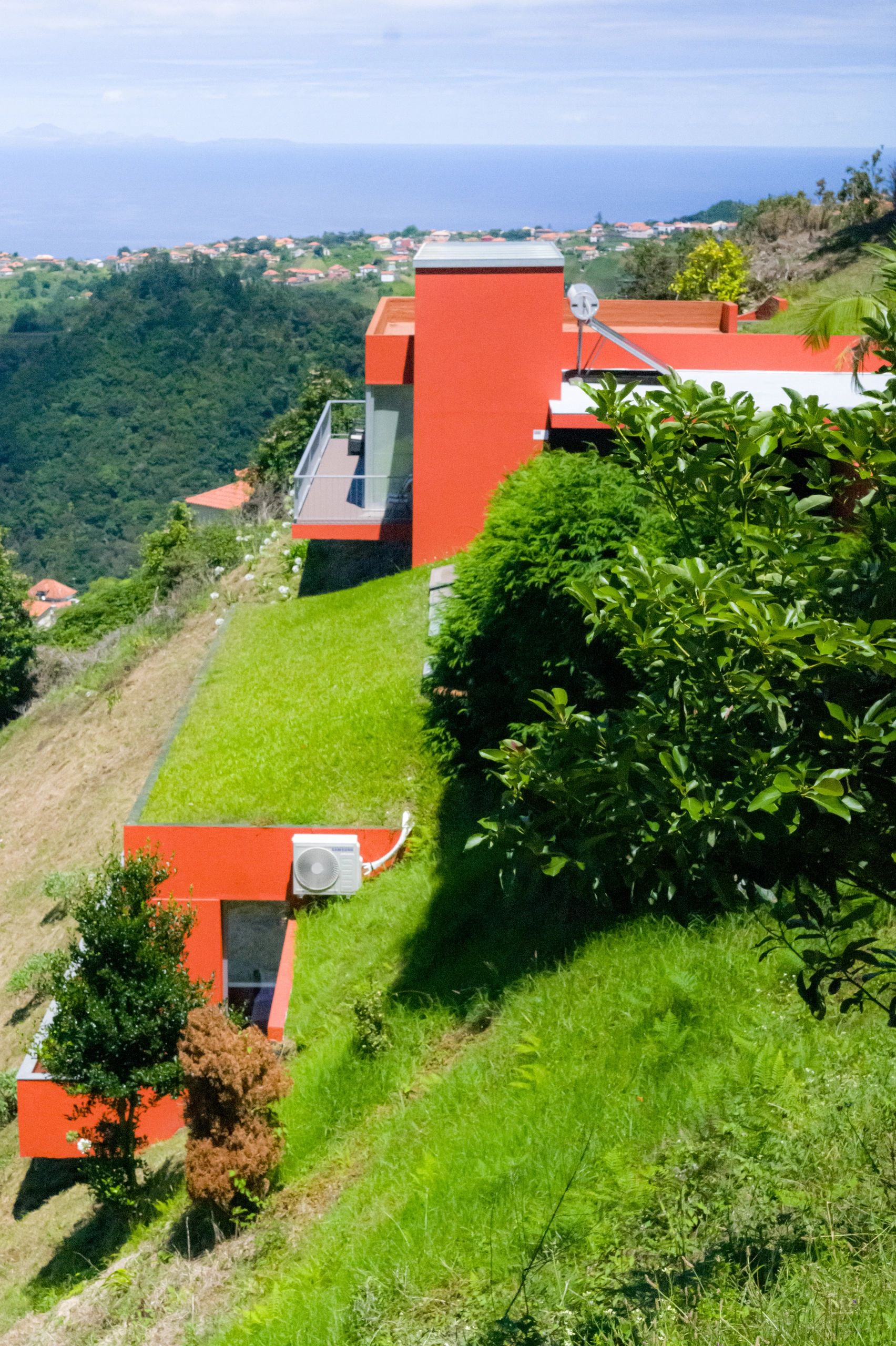Two orange levels stepped down the green slope, with the coast beyond