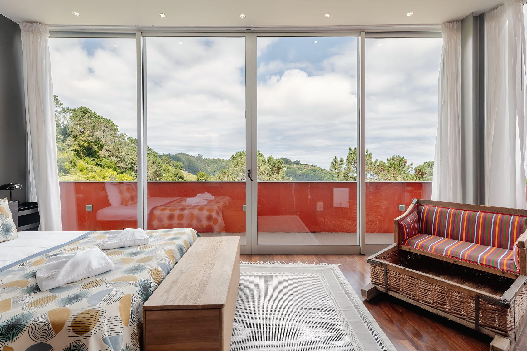 From the master suite, glass onto the orange terrace and the forest beyond