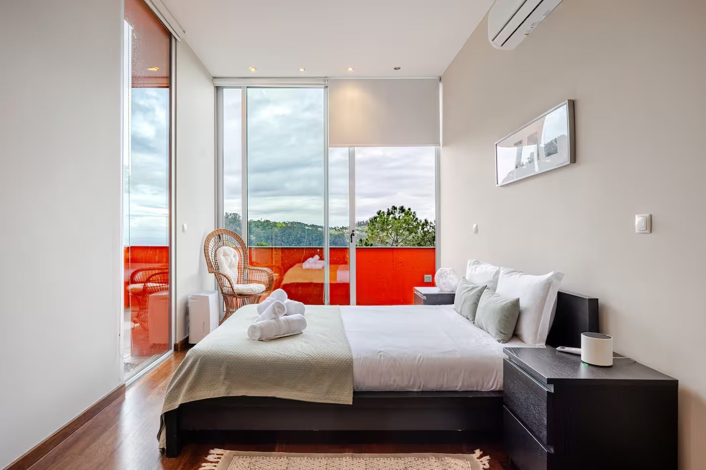 Gästezimmer mit Blick zur orangefarbenen Terrasse, Korbsessel und Hang