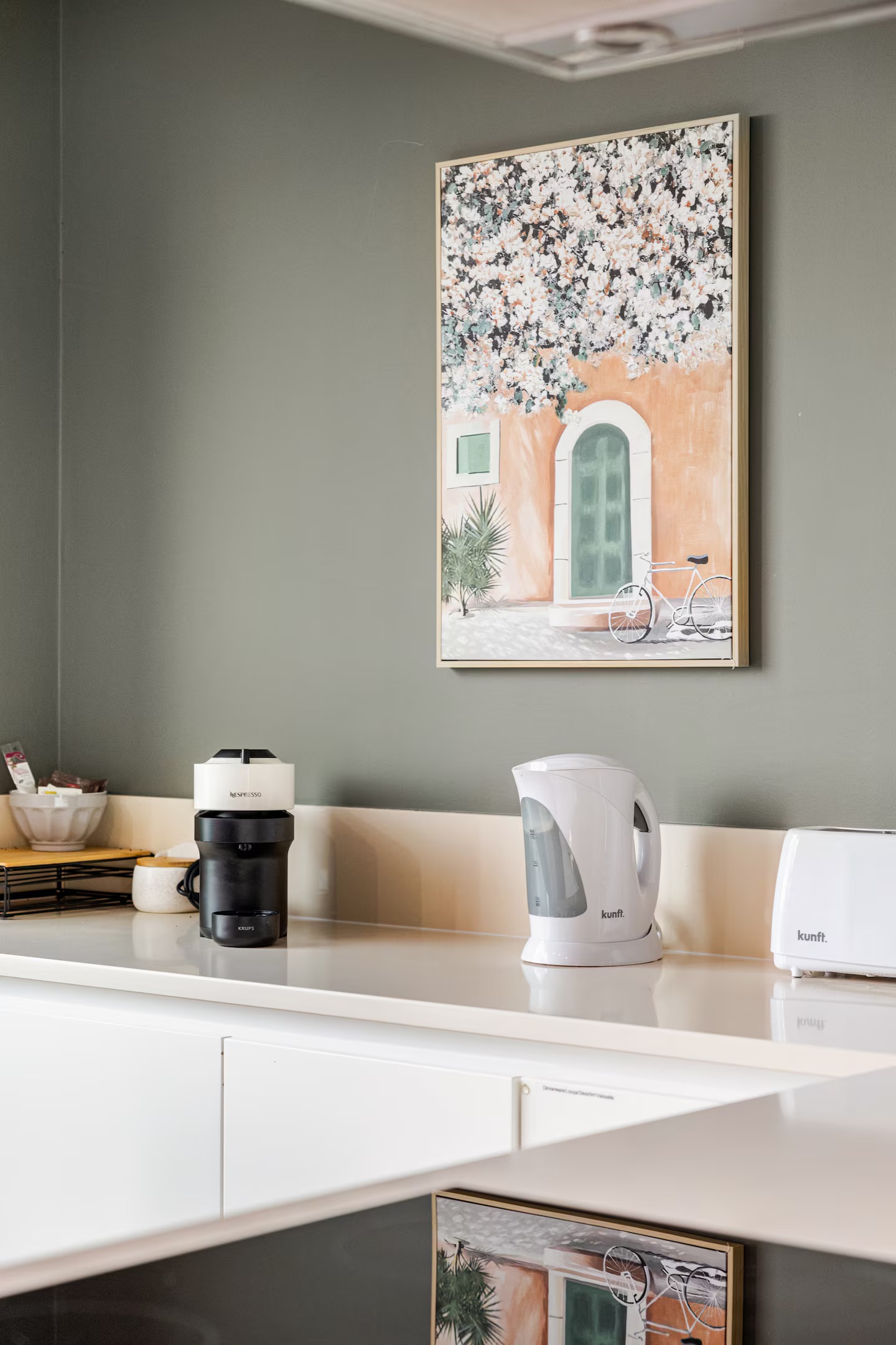 Kitchen counter with Nespresso, kettle, and toaster against a sage wall