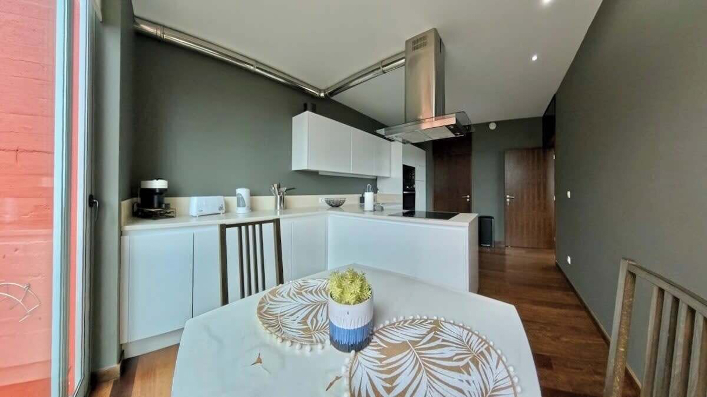 Kitchen and dining table against a dark wall, with the orange terrace outside