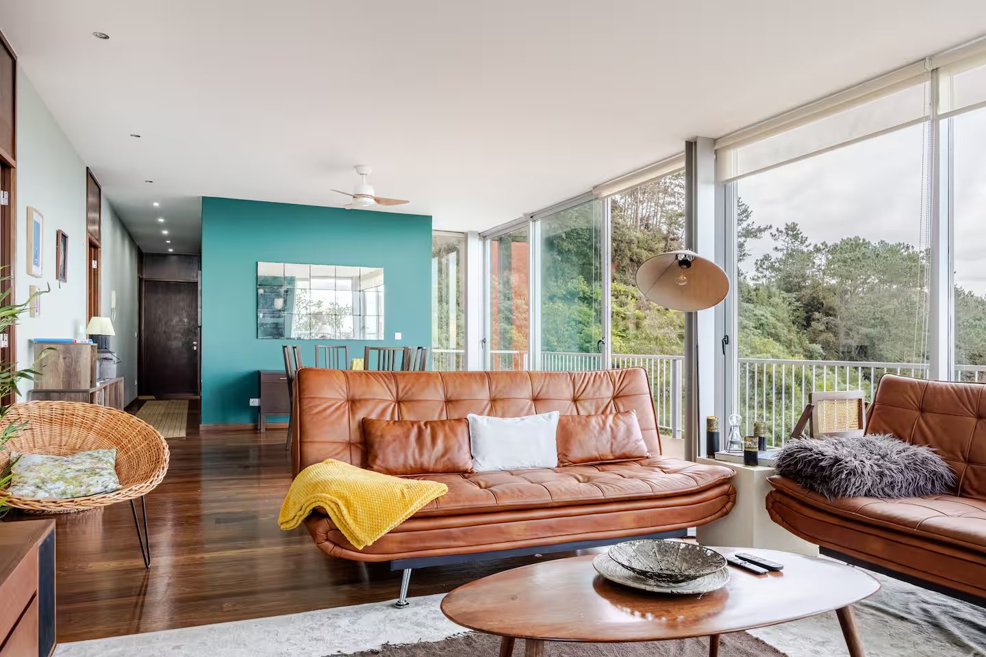 Wohnzimmer mit Ledersofas, gelber Decke und bodentiefen Fenstern zum Hang