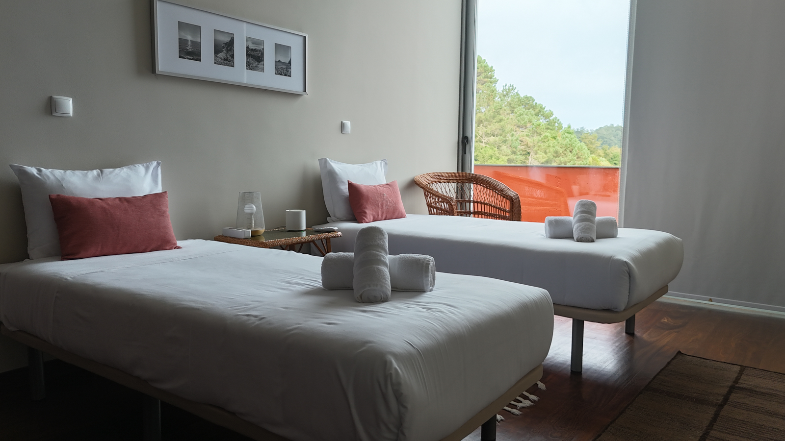 Twin guest room with two single beds, terracotta pillows, and an orange balcony