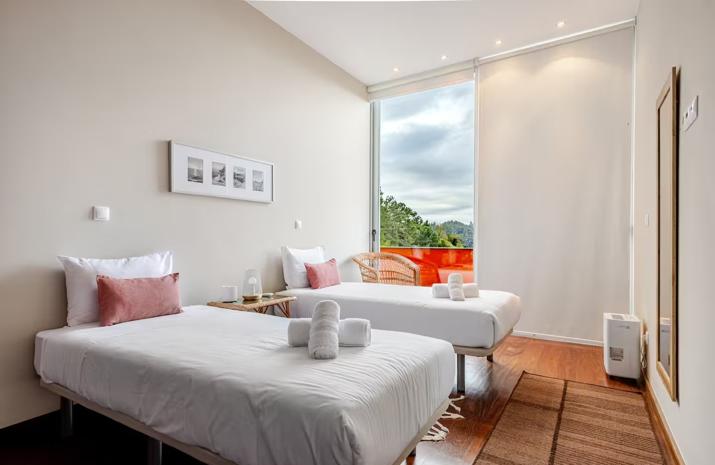 Twin guest room with two single beds, pink pillows, and an orange balcony