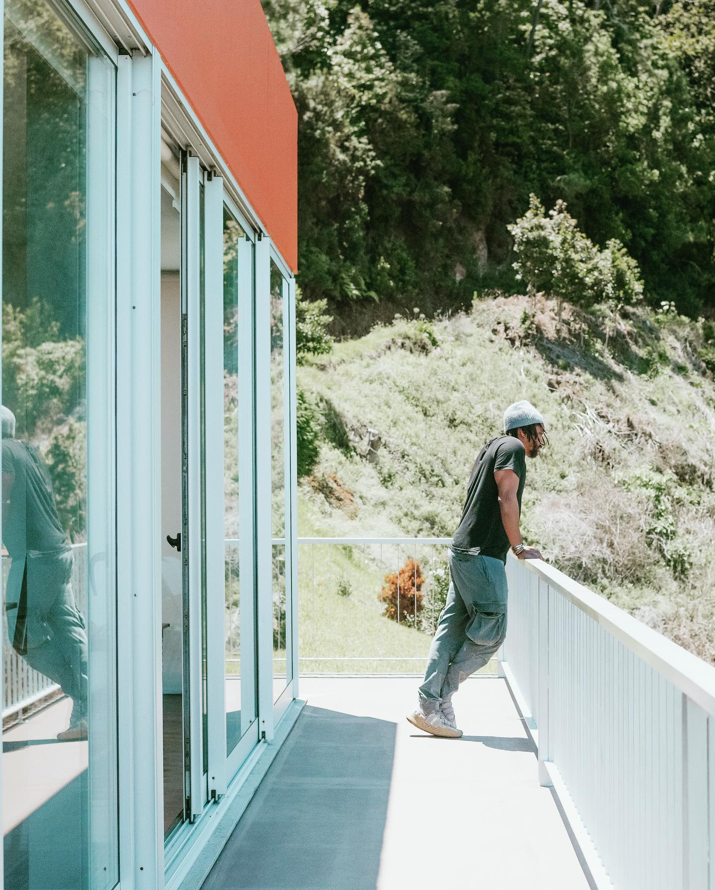 Keem on the orange villa balcony, looking toward the forested hillside